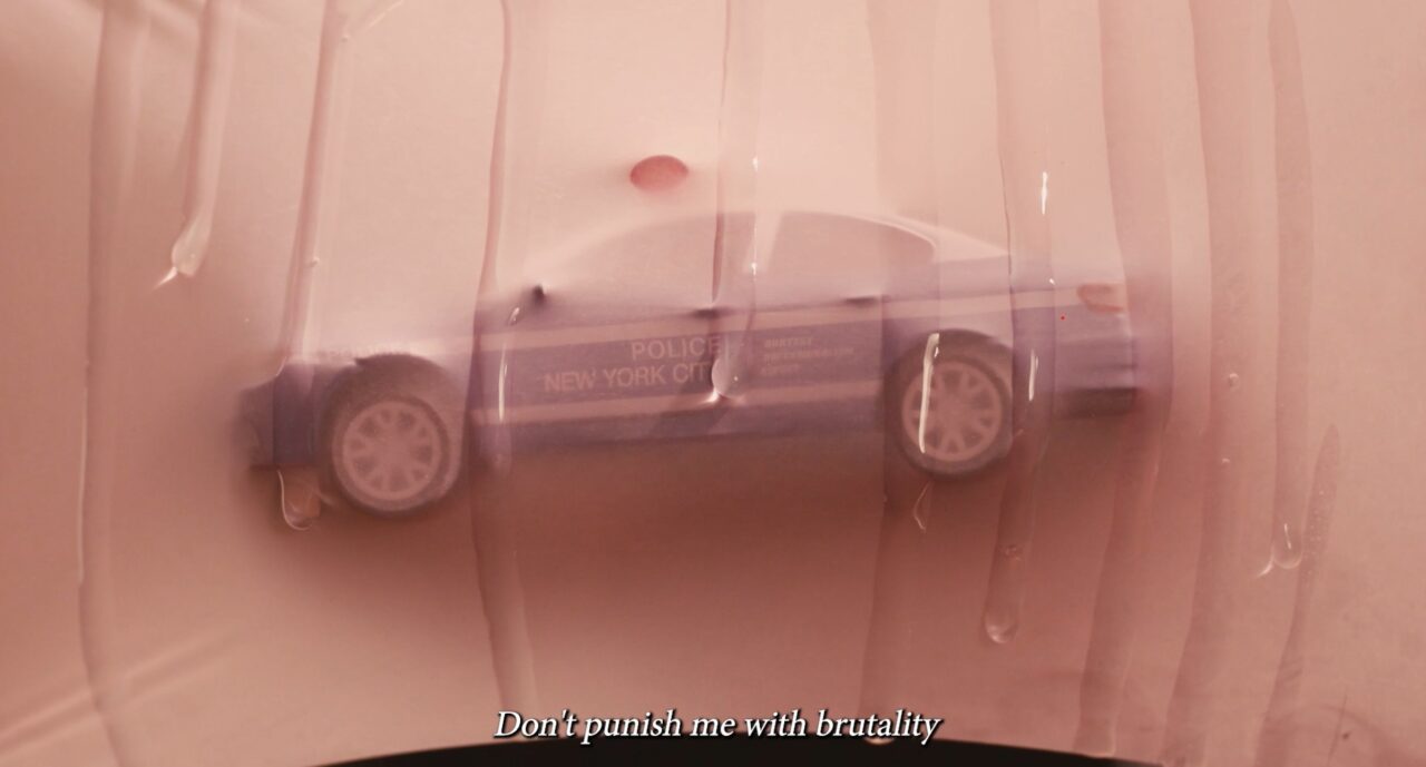 Kleinmodell eines blauen Polizeiautos eingeklemmt zwischen transparenten Folien.
