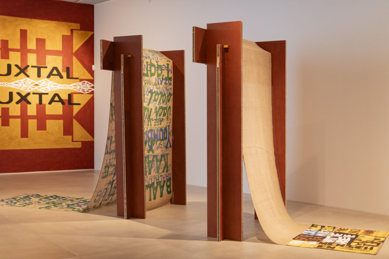 Art installation featuring colorful textiles and walls, creating a modern exhibition setting.