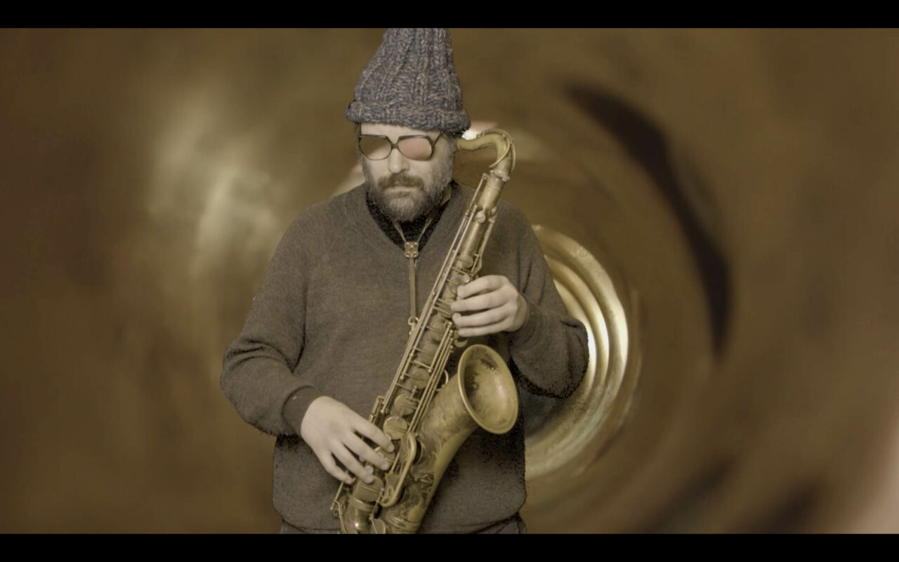 Man in a hat plays saxophone against a blurred, circular background.