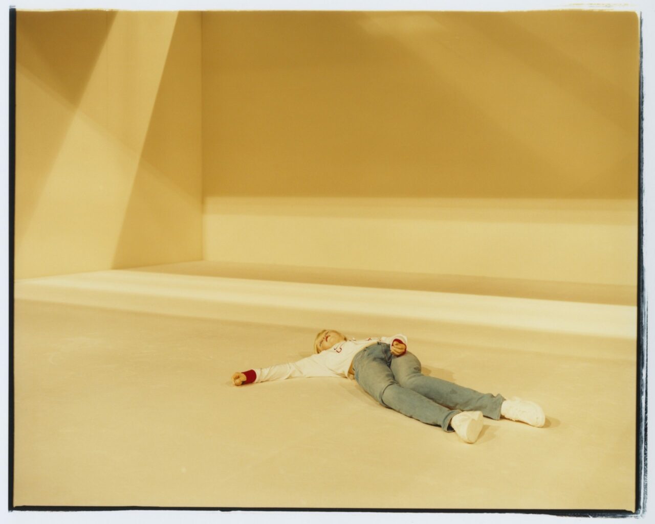 Person in casual clothing relaxes on a bright, minimalist floor.