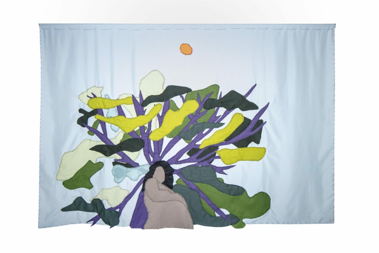 Colorful wall decoration featuring a seated figure and stylized plants, surrounded by a light blue sky and the sun.