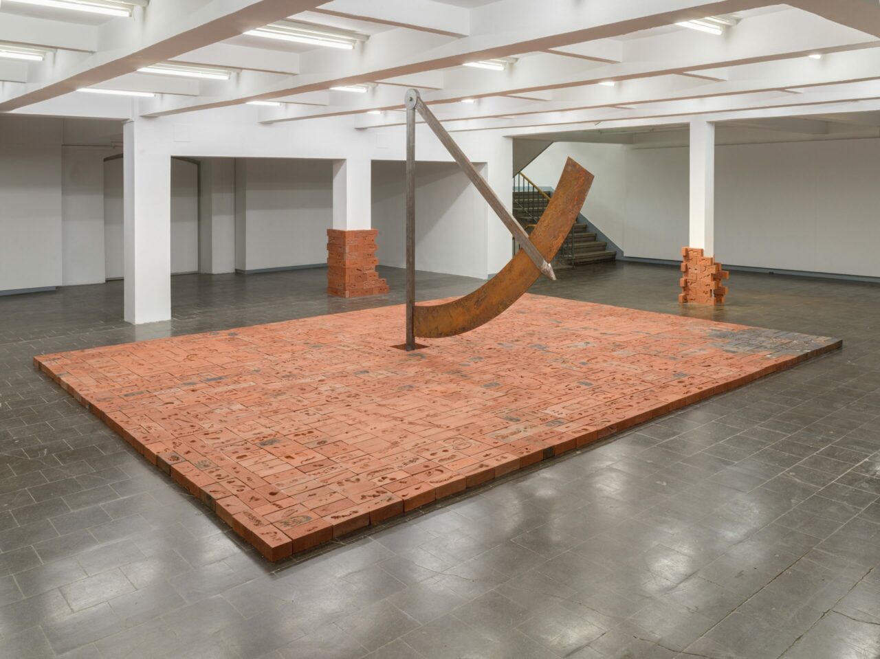 Sculpture made of metal and bricks in a spacious, bright, modern exhibition room.