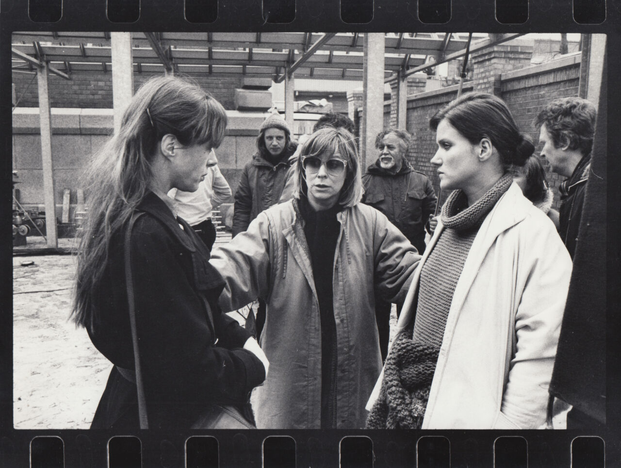 Drei Frauen im Bauumfeld im Gespräch; eine erteilt Anweisungen, während die anderen aufmerksam zuhören.