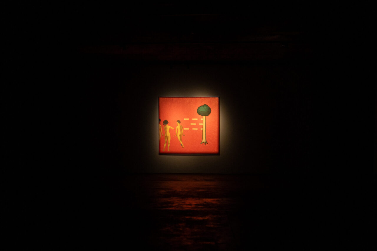 A lit painting in a dark room shows two figures and a tree against a red background.