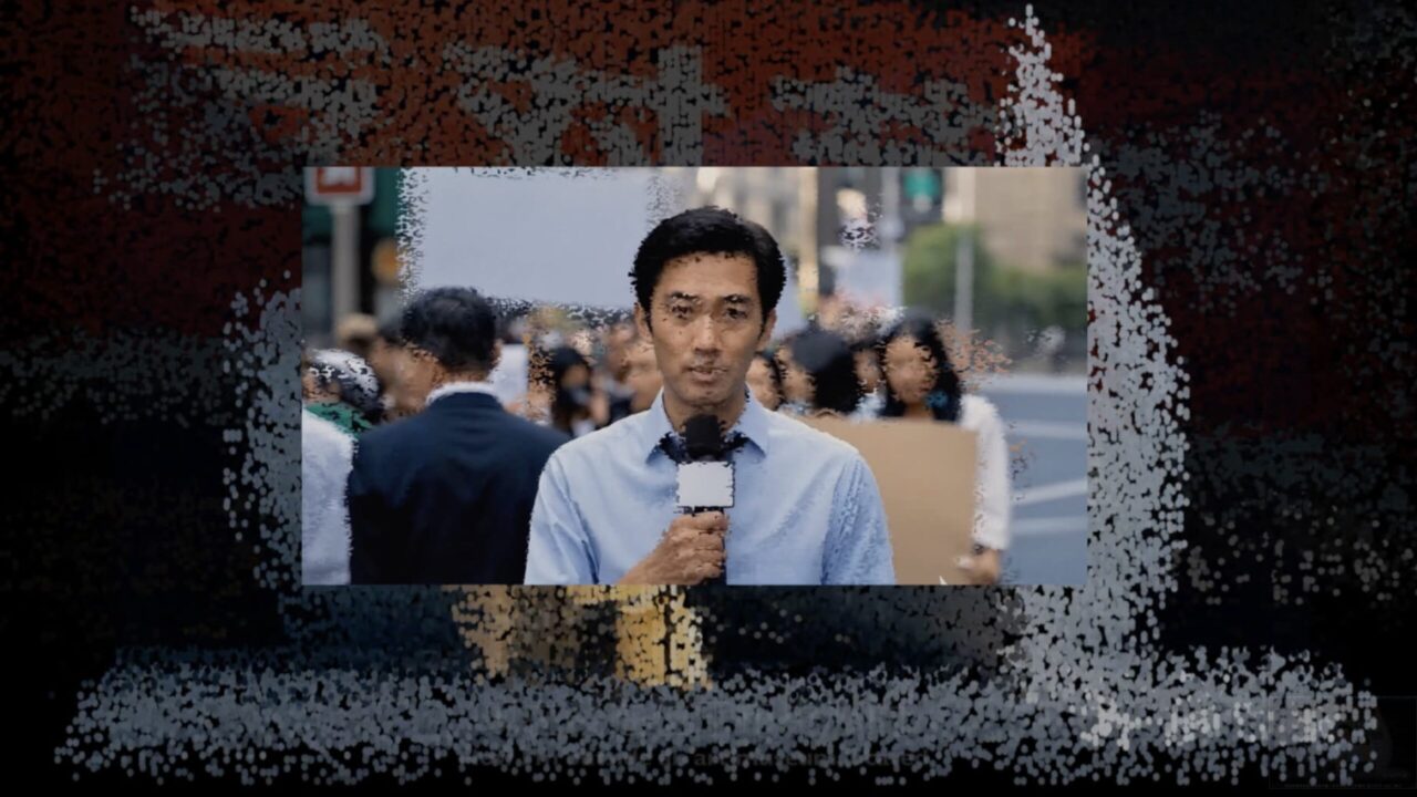 Ein Reporter spricht mit einem Mikrofon vor einer Menschenmenge auf der Straße.