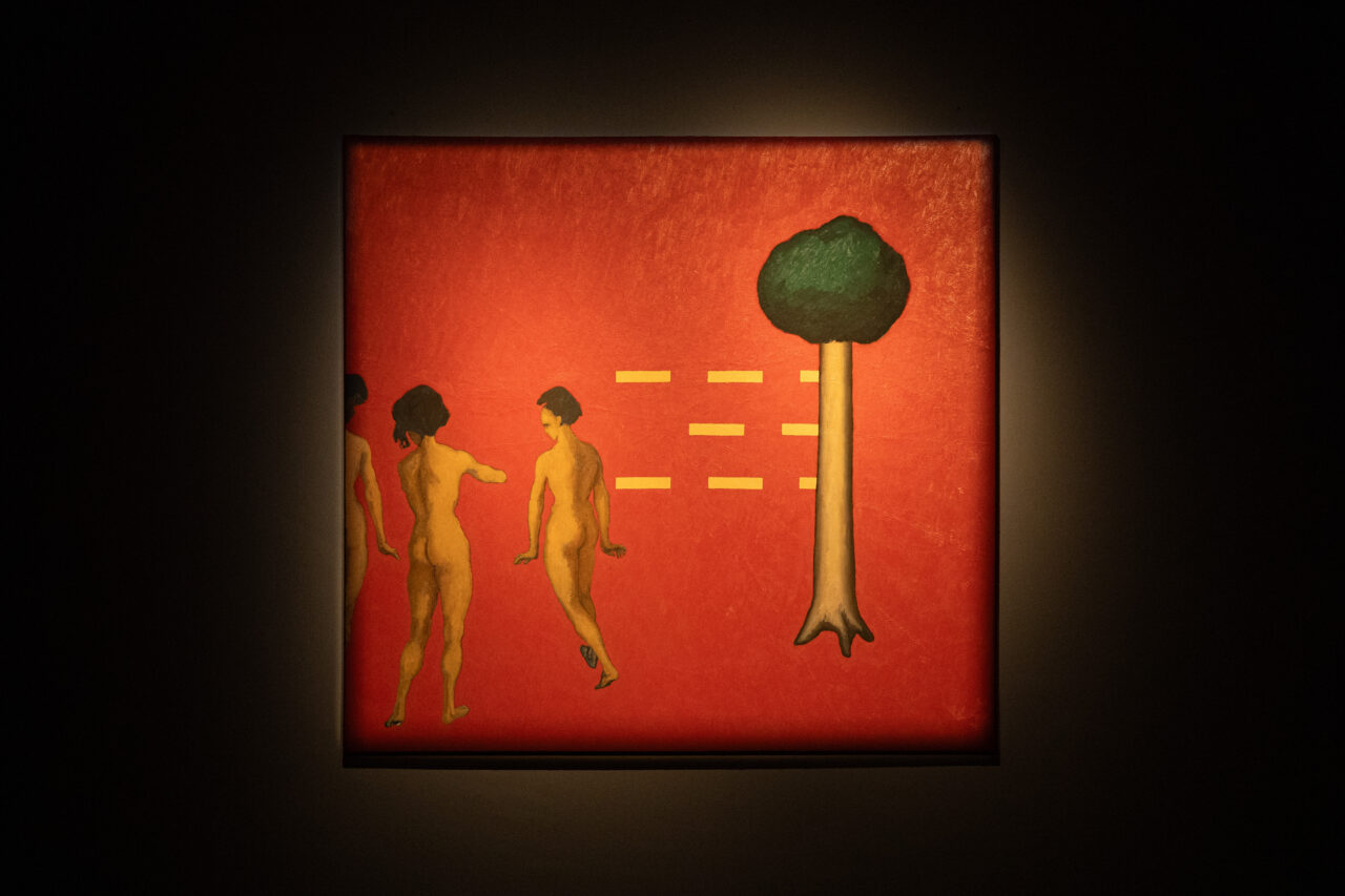Naked figures against a bright red background, next to a tree and parallel lines. A work with symbolic character.