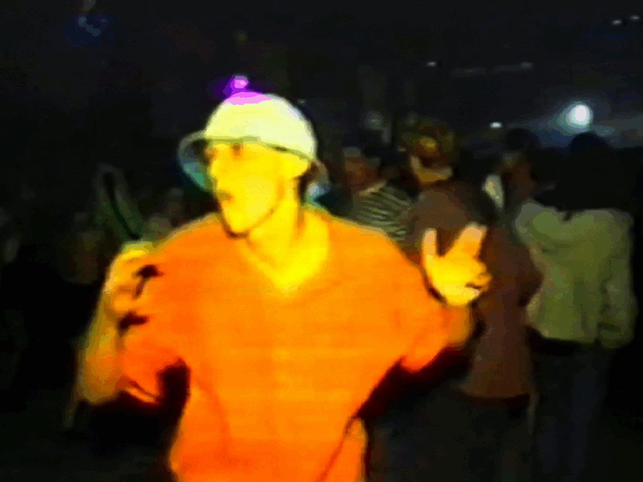 A man dances in a club with colorful lights and a lively atmosphere, surrounded by other partygoers.