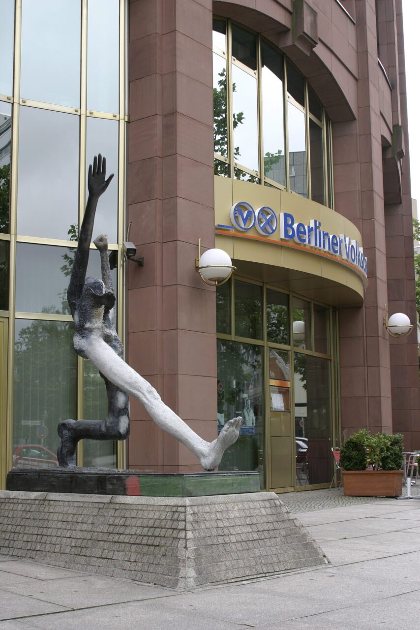 Sculpture of a human body in front of a modern building with the inscription "Berliner Volksbank."