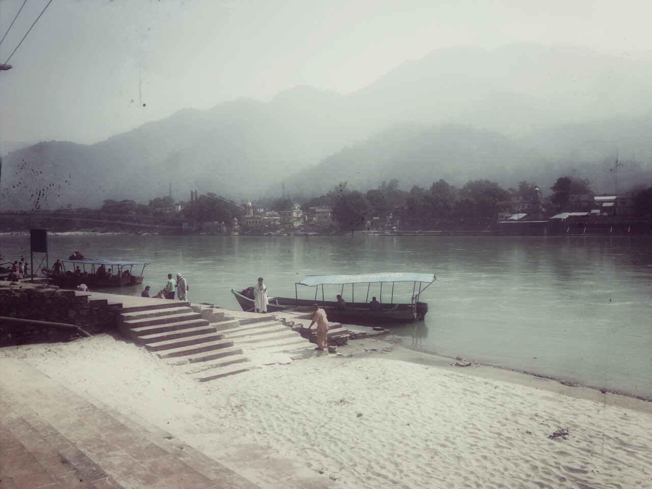 Coastal view with piers, boats in the water, and mountains in the background, surrounded by a misty atmosphere.