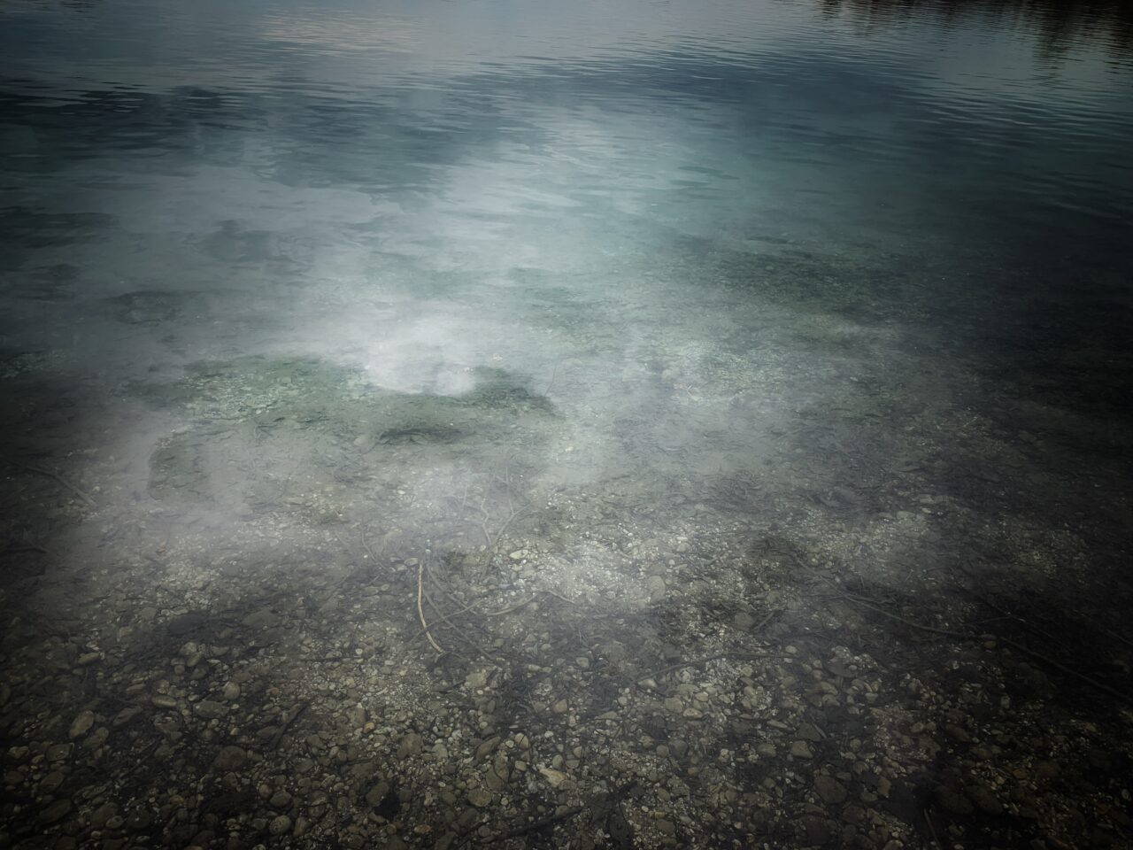 Calm water surface with crystal clear bottom, rippled by gentle waves and soft play of light.