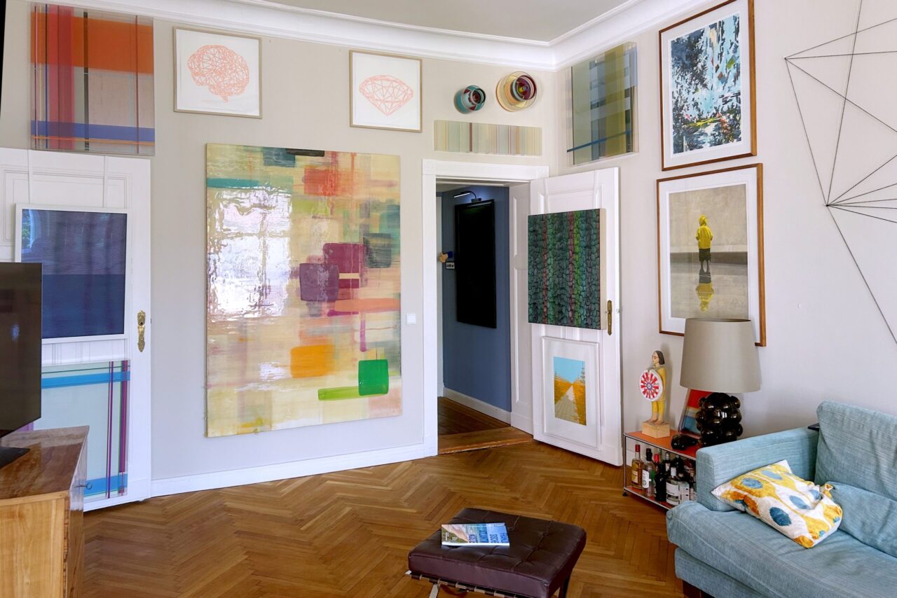 Bright and artistic living room featuring colorful wall art, a cozy couch, and wooden flooring.