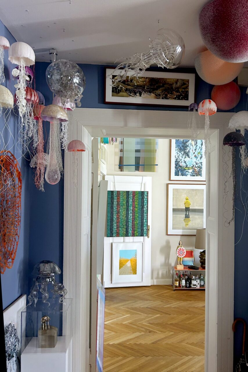 Artistic hallway decorated with colorful jellyfish sculptures and framed artworks on blue walls.