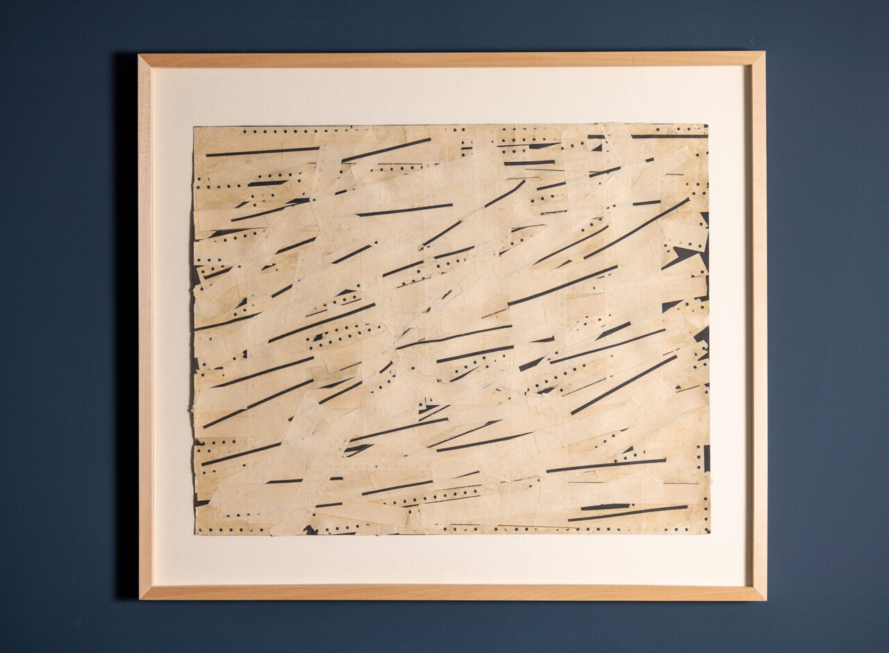 Abstract art piece featuring a textured, beige background with black lines and patterns, framed against a blue wall.