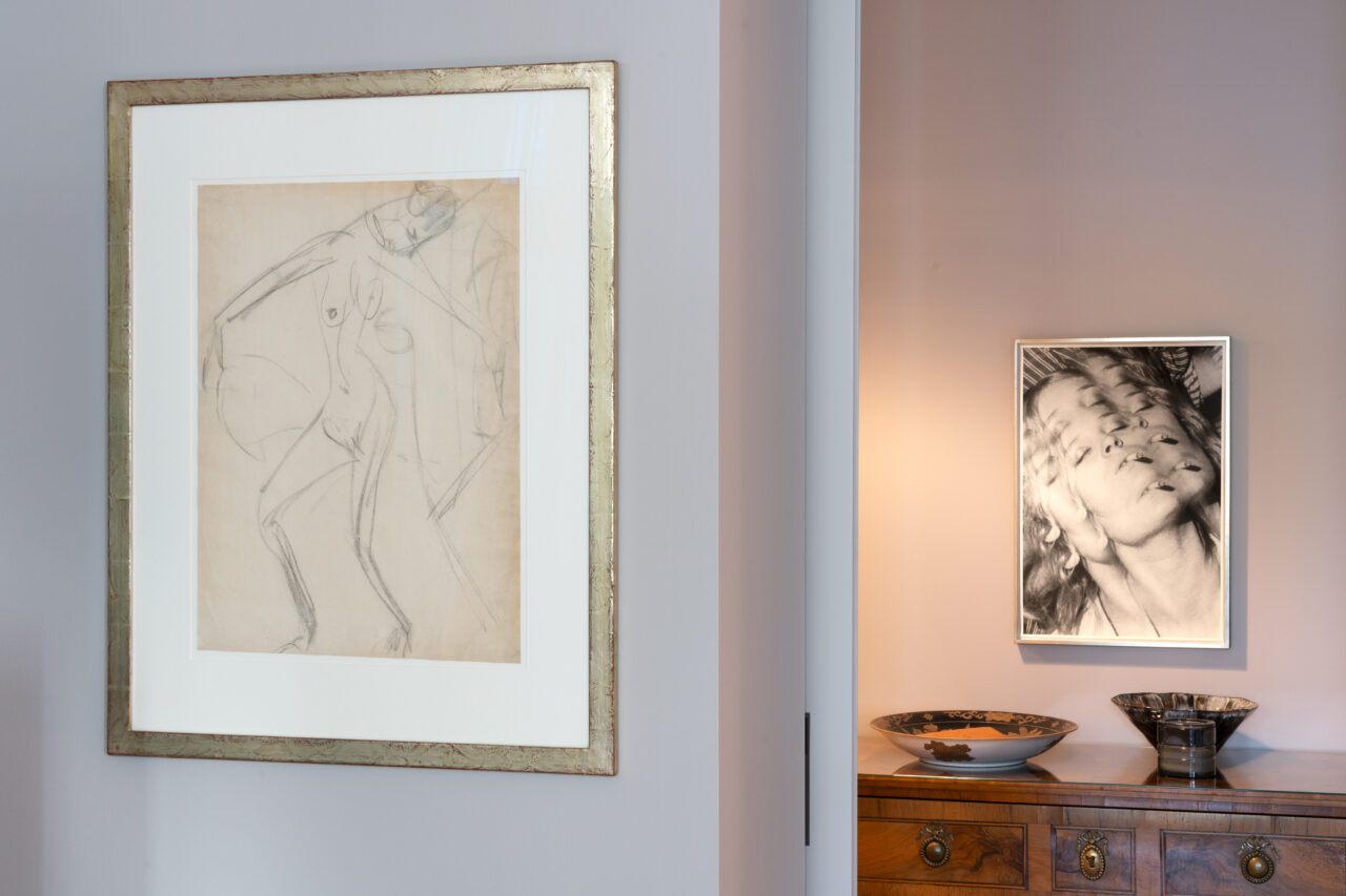 Two framed artworks: a sketch of a figure on the left and a multidimensional portrait on the right on a wall.